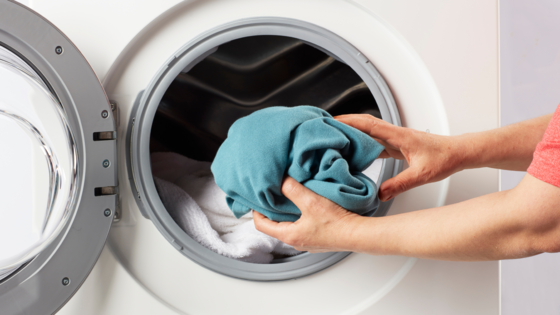 arm putting laundry inside washing machine